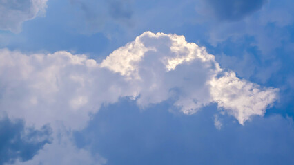 The serene celestial canvas features fluffy white clouds floating in a bright blue sky