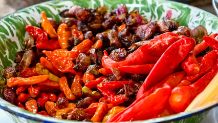 Close-up view of a bowl containing bright red chilies and ingredients being cooked to make chili sauce