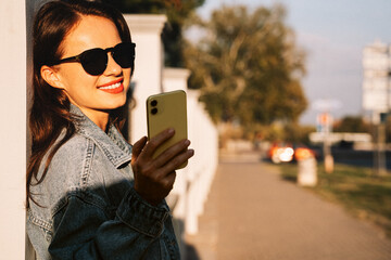 Woman wearing sunglasses checking her smartphone on city street