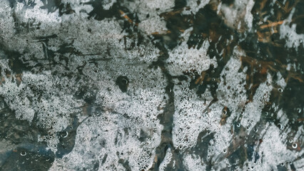 Abstract view of dew on plastic with foamy texture and dark organic elements
