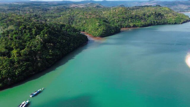Aerial view flying over tropical blue ocean towards beautiful green mountains and white sandy beach. sendang biru Bay, East Java Indonesia