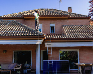 Technician installing solar panel on house roof