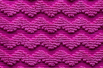 Vibrant texture of pink fabric with intricate patterns creates a striking visual display in handmade textile art