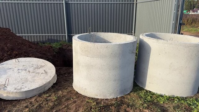 Concrete rings for sewage. Precast concrete rings on the land plot with gray fence