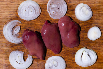 Fresh ingredients come together for savory dishes with onions and chicken livers on a wooden cutting board