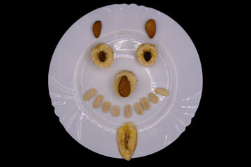 Creative fruit arrangement creates a joyful face on a white plate against a dark background