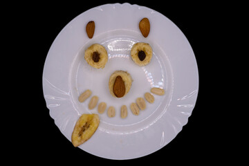 Creative fruit arrangement forming a cheerful smiley face on a white plate