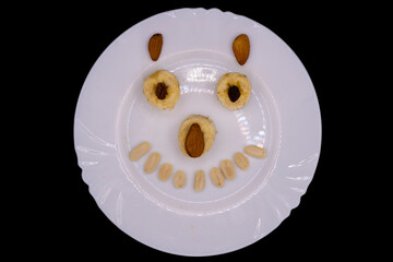 Delightful dessert creation with playful face using fruits and nuts on a white plate during a cheerful gathering