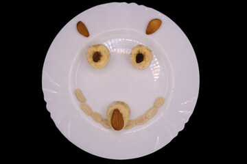 Creative dessert art made with fruits and nuts on a white plate, creating a cheerful face for kids to enjoy during snack time