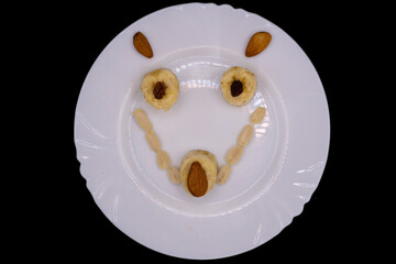 Creative food art using fruits and nuts to create a smiling face on a white plate