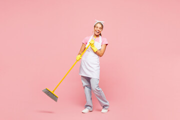 Full body young happy woman wears white apron hold mop broom pov microphone sing song while...