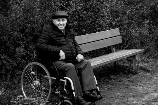 Elderly man sitting in wheelchair smiling while taking a break from outside walk
