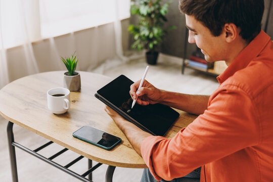 Close up young graphic designer man in casual clothes work use write draw stylus pc pen sit alone at table in coffee shop cafe relax rest in free time indoor. Freelance mobile office business concept. - Powered by Adobe