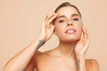 Beautiful sexy half naked topless young woman 20s with nude make up wearing patch under eye isolated on plain beige color background studio portrait. Skin care healthcare cosmetic procedures concept.