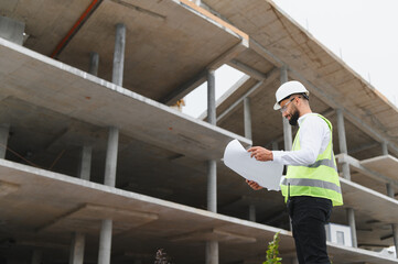 Fototapeta premium Engineer examining blueprints at a construction site