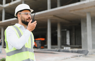 Construction worker communicating using walkie talkie at building site