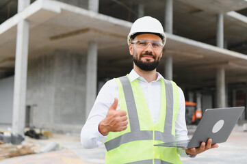 Construction engineer giving thumbs up holding laptop