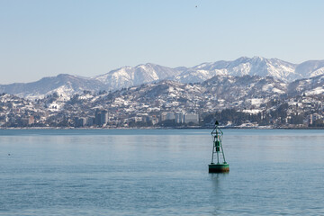 Winter seascape with navigation buoy and dramatic snowy mountain range backdrop © TashaAsha