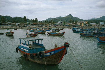 Panoramic view traditional shabby boats filled with goods moored on river at small seaside town....