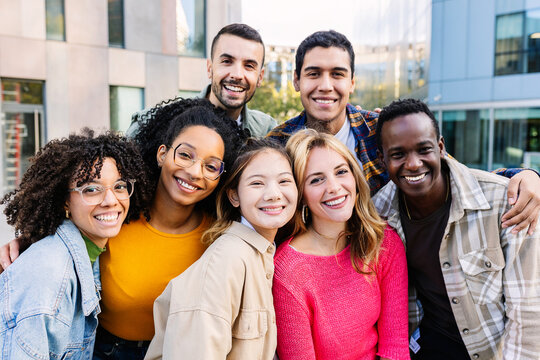 Fototapeta Portrait of young group of diverse people smiling at camera standing outdoor. Happy millennial college students enjoying time together, social gathering and hanging out at city street.
