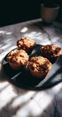 Four baked muffins with crumb topping on a black plate, dappled sunlight and a cup