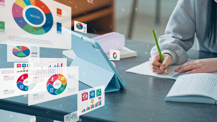 A girl studying while looking at a tablet and statistical data