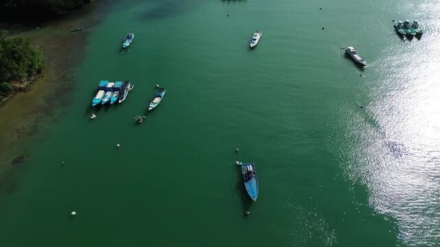 Aerial view of fishing boats floating on the calm green waters of Sendang Biru Beach, Malang, East Java