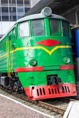 Green railway locomotive on the rails. Close-up