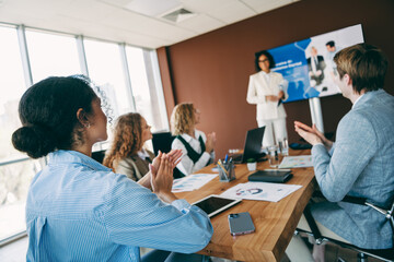 Professional team applauding presentation during meeting in corporate office with diverse colleagues working together