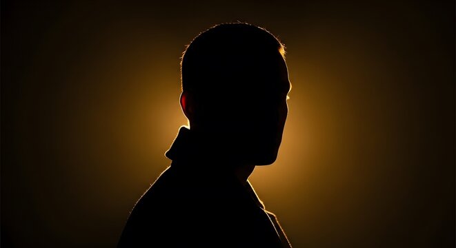Profile silhouette of a man's head and shoulders against a bright, warm backlight.