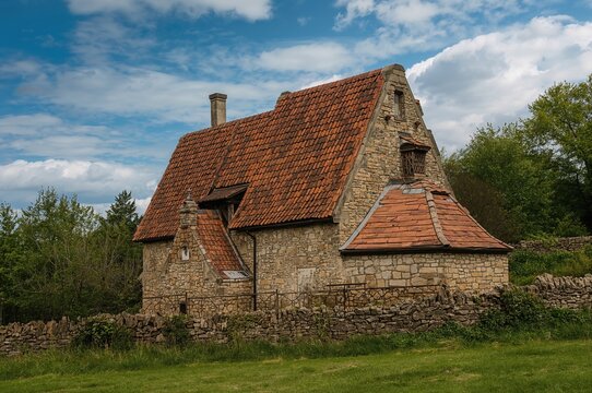 Image of an ancient stone cottage featuring a unique wooden shingle roof - Powered by Adobe