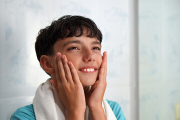 Hygiene, hormonal changes, skin care, and adolescence. Preteen boy stroking his cheeks