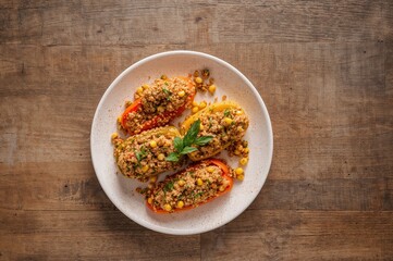 Top-down view of corn and quinoa-filled bell peppers on a rustic wooden surface with room for text