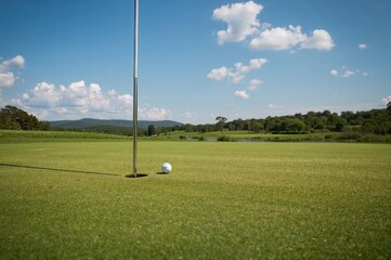 Obraz premium Golf ball positioned near hole on practice putting green with flagstick