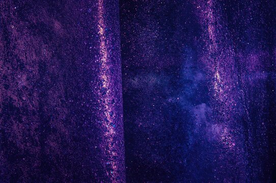 Vibrant purple hues with glossy accents. Textile surface illuminated by shimmering iridescence. Coarse backdrop featuring multicolored sparkling dots.