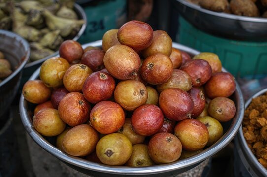 Hog plum fruits displayed in a metal bowl at an outdoor food market