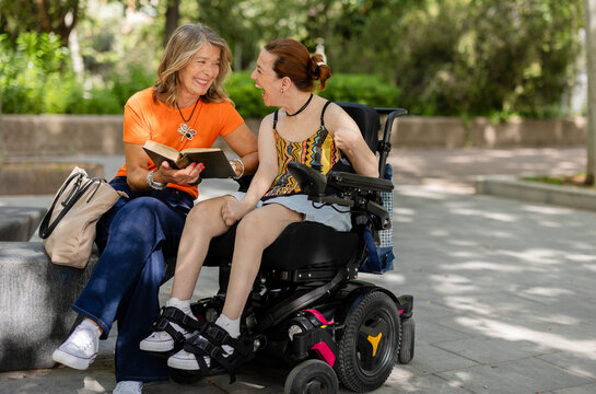 Mother and daughter enjoying reading and laughing in park