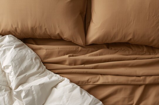 Close-up of brown bedding with beige pillow and white comforter, featuring an ivory blanket and off-white bedspread in a bedroom flatlay, king size cream cover, mustard duvet, and ruffled bedcover set