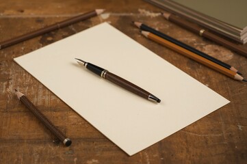 A sheet of A4 paper and a pen resting on a rustic wooden surface