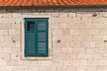 Green shuttered window on a stone wall in Dubrovnik, Croatia during daytime