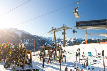 Sunny winter day on alpine slope with skis and snowboards resting near gondola station. Bright sunlight, blue sky, and mountain panorama create atmosphere of adventure, freedom, and relaxation