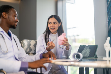 Doctors discussing cardiology case using heart model and digital scan, cardiovascular health, medical training and heart anatomy explanation, modern medical training team education, heart disease