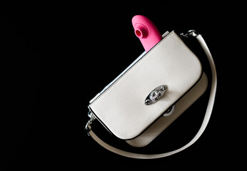 Pink vibrator, partially visible from white handbag, on dark blurred background.