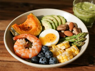 A vibrant bowl loaded with shrimp, roasted pumpkin, boiled eggs, corn, almonds, blueberries, mushrooms, and asparagus, paired with a creamy avocado smoothie