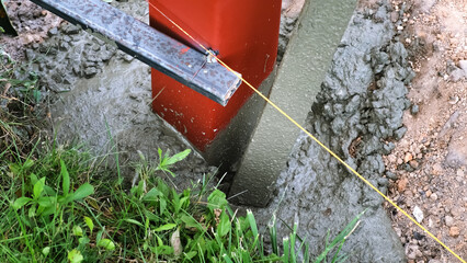 The worker is tamping a poured concrete. Compaction of the cement mixture. Pouring wet concrete from a mixer truck into a pit with pillar. Foundational work. Building industry. High quality photo.