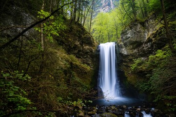 Obraz premium Extended shutter capture of flowing waterfall scenery with water, travel, nature, trees, springtime, landscape, woodland, hills, and lush greenery