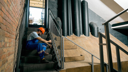 Engineer resting on stairs after technical inspection work. Concept of occupational safety,...