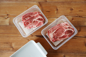 top view of fresh raw pork neck steaks in plastic trays on wooden table