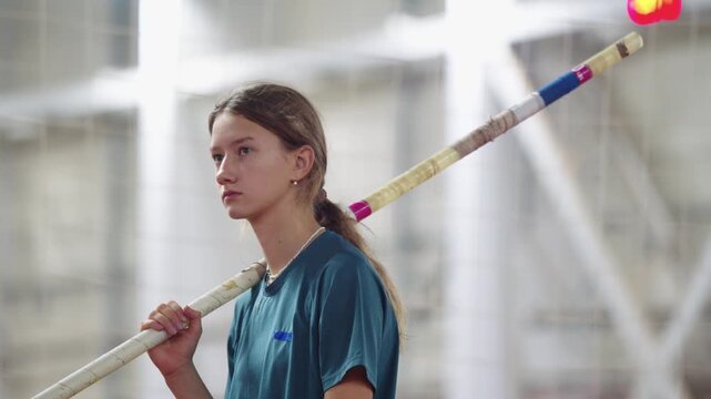 Young female pole vaulter concentrating before jump