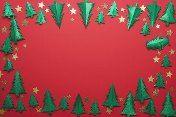 Holiday greeting banner featuring green shiny Christmas trees and golden star confetti on a red backdrop. Minimalist festive design with space for text.